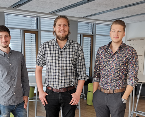 Drei junge Gründer aus Würzburg, junge Männer im Hemd, Büroraum, AlphaOmega